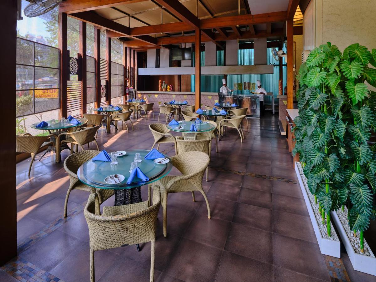 a restaurant with tables and chairs and plants at Sayaji Pune in Pune