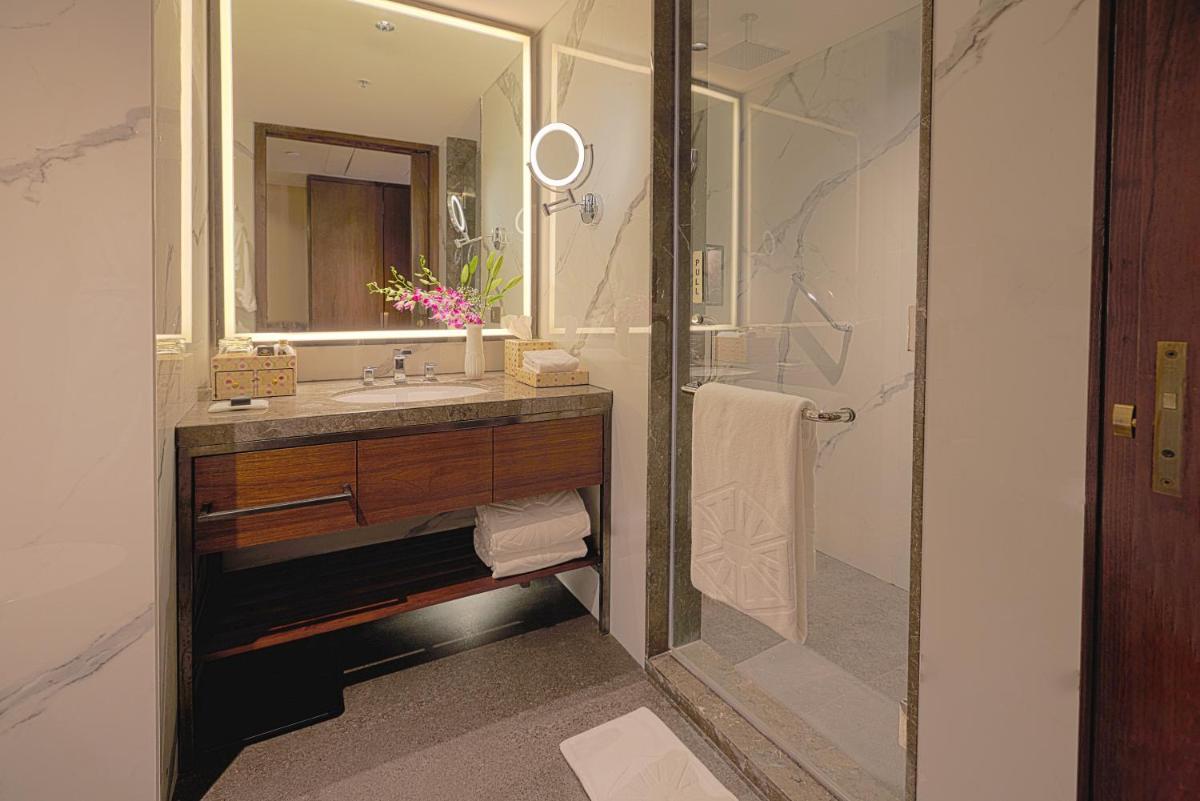 a bathroom with a sink and a mirror at Taj Bangalore in Devanahalli-Bangalore