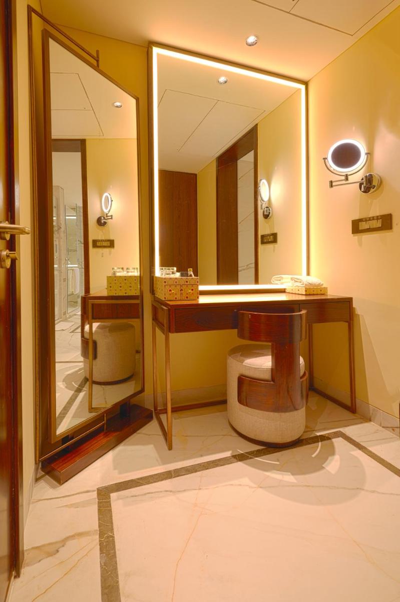a bathroom with a toilet and a large mirror at Taj Bangalore in Devanahalli-Bangalore