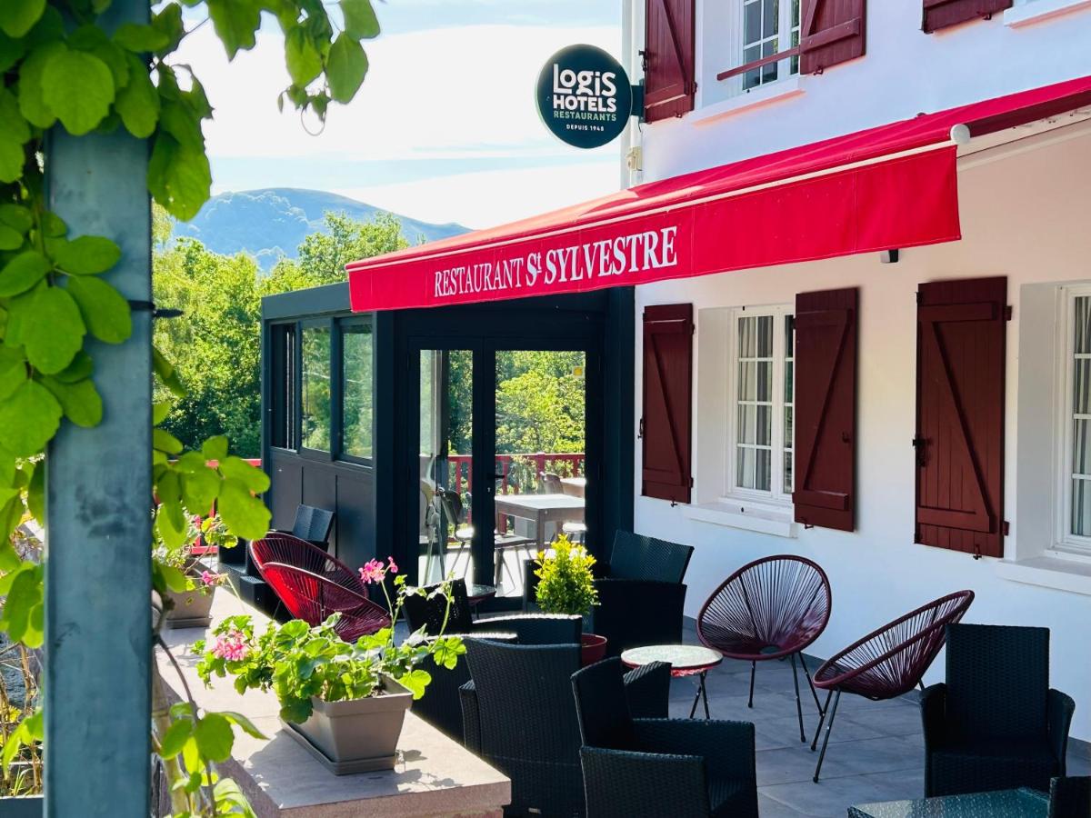 un patio avec des chaises et des tables à l'extérieur d'un bâtiment dans l'établissement LOGIS Hôtel St Sylvestre, à Aldudes