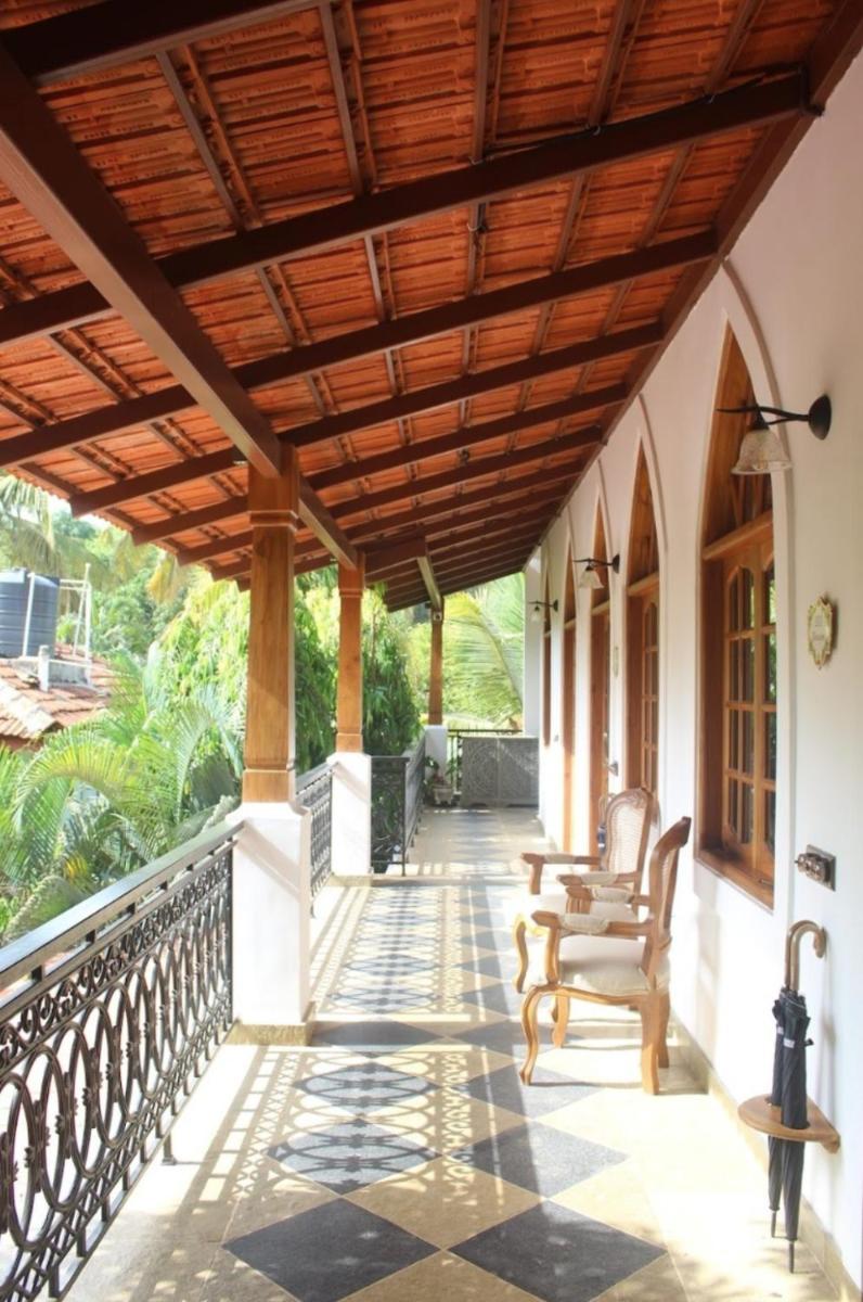a porch with chairs and a wooden ceiling at The Postcard Saligao in Calangute