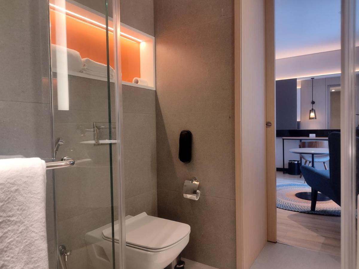 a bathroom with a toilet and a glass shower door at Hyatt Centric Hebbal Bengaluru in Bengaluru