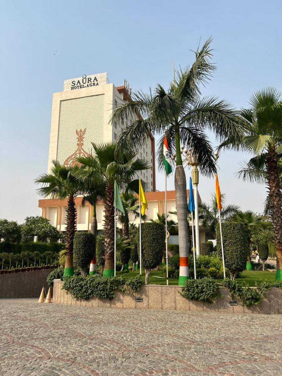 a building with palm trees and flags in front of it at Saura Hotel, Agra - A Club Mahindra Associate in Agra