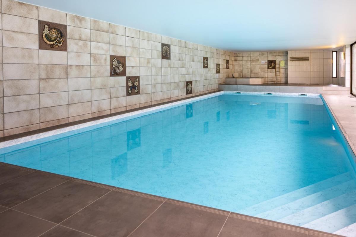 une grande piscine avec de l'eau bleue dans l'établissement Logis Hostellerie Motel Au Bois Le Sire, à Orbey