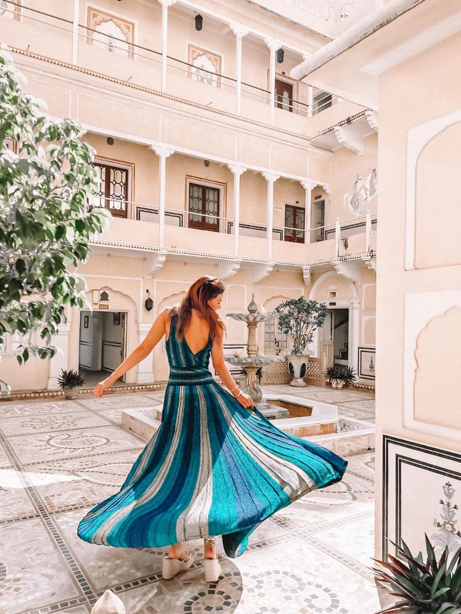 a woman in a blue dress walking in a building at The Raj Palace (Small Luxury Hotels of the World) in Jaipur