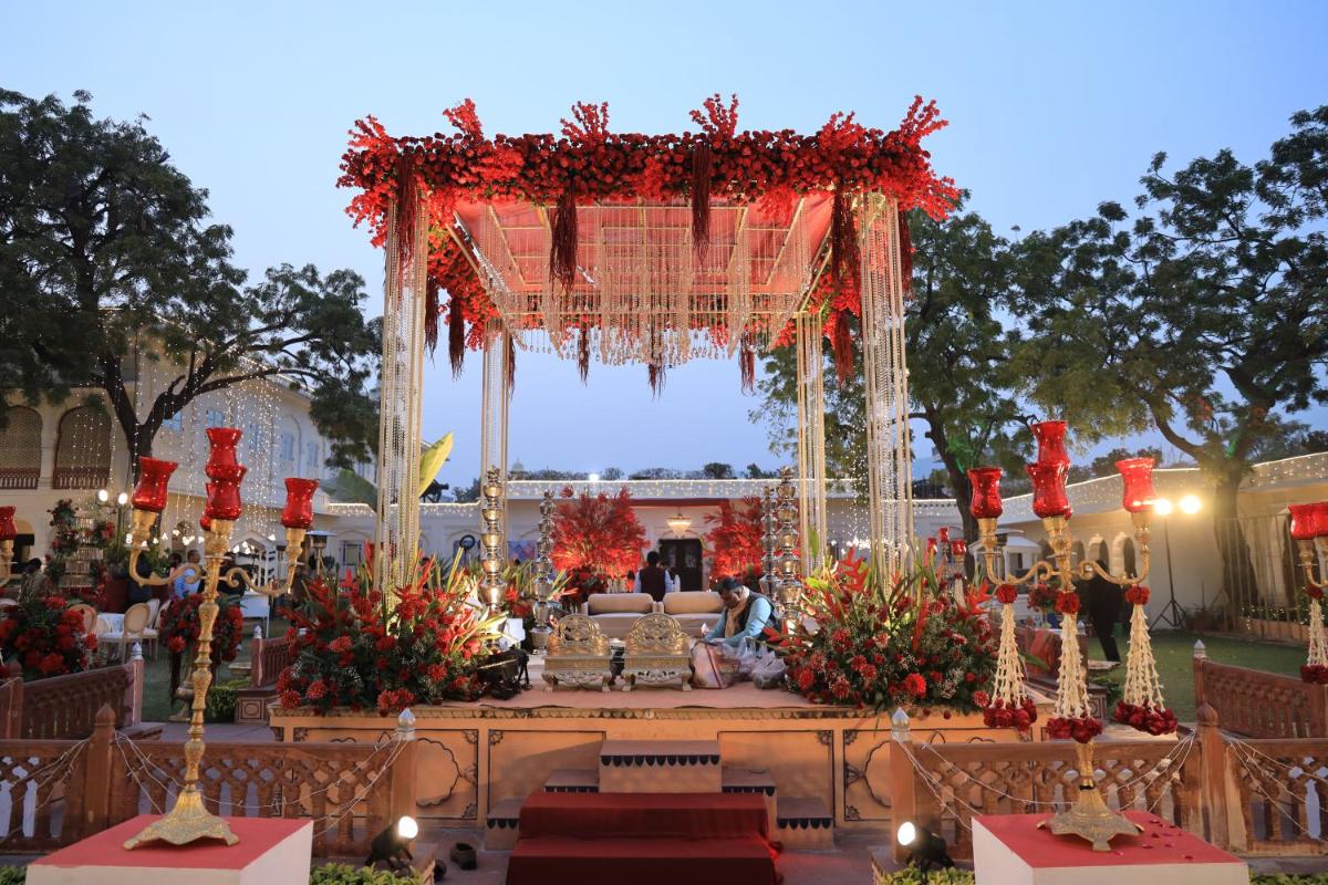 an outdoor ceremony with a large arch with red flowers at The Raj Palace (Small Luxury Hotels of the World) in Jaipur