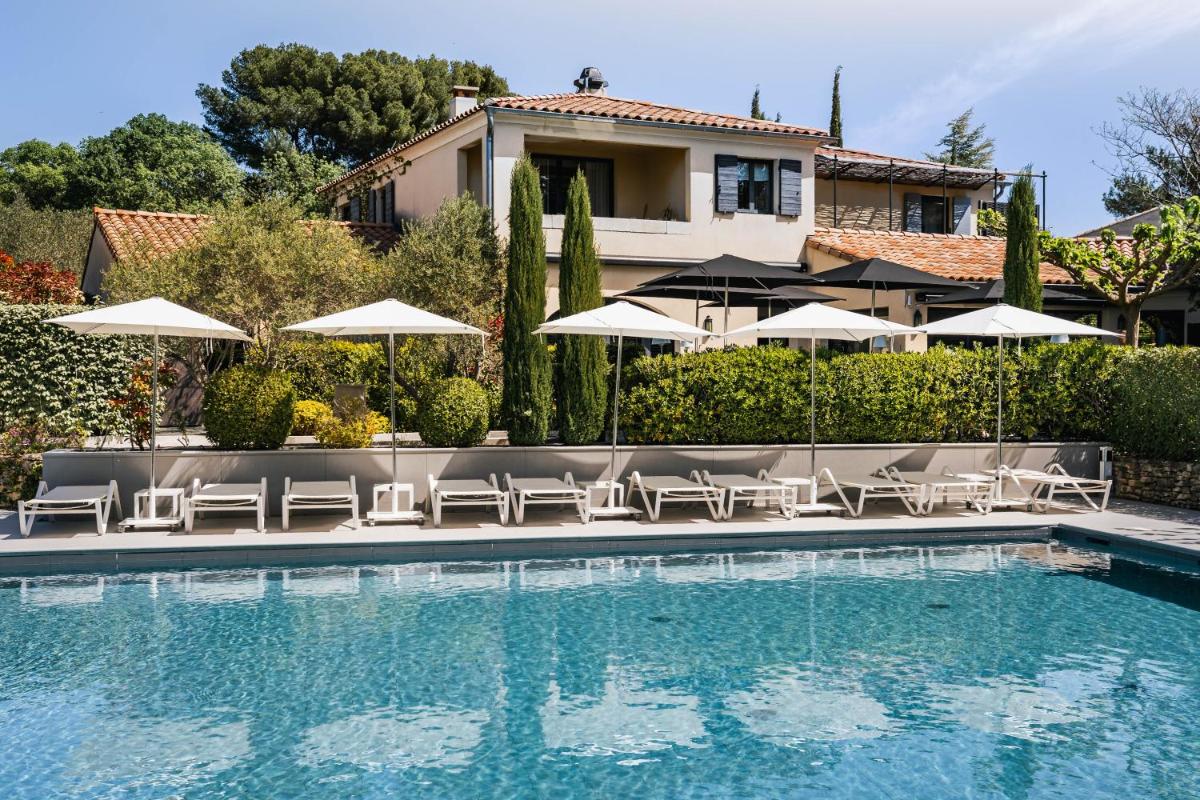 une piscine avec chaises longues et parasols à côté d'une maison dans l'établissement Du Côté Des Olivades, à Paradou