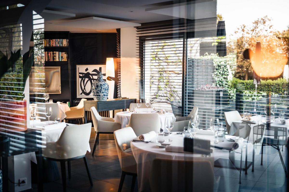 un restaurant avec des tables et des chaises blanches et une fenêtre dans l'établissement Bdesign & Spa, à Paradou