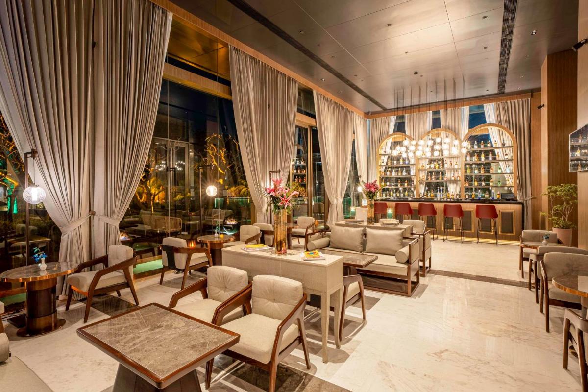 a hotel lobby with tables and chairs and windows at Radisson Blu Hotel Amritsar in Amritsar