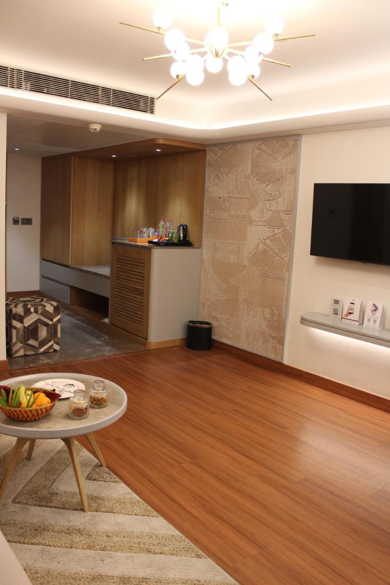 a living room with a table and a flat screen tv at Pride Plaza Hotel, Ahmedabad in Ahmedabad
