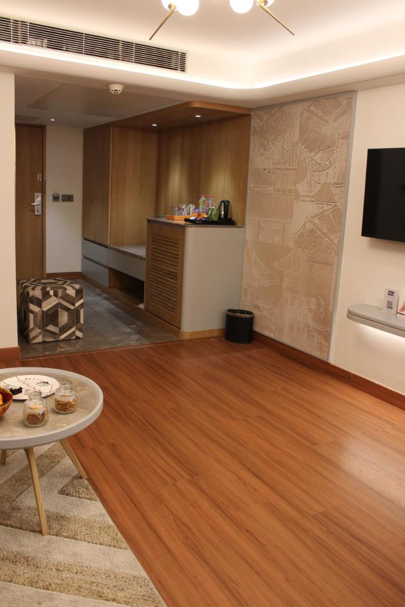 a living room with a wooden floor and a flat screen tv at Pride Plaza Hotel, Ahmedabad in Ahmedabad