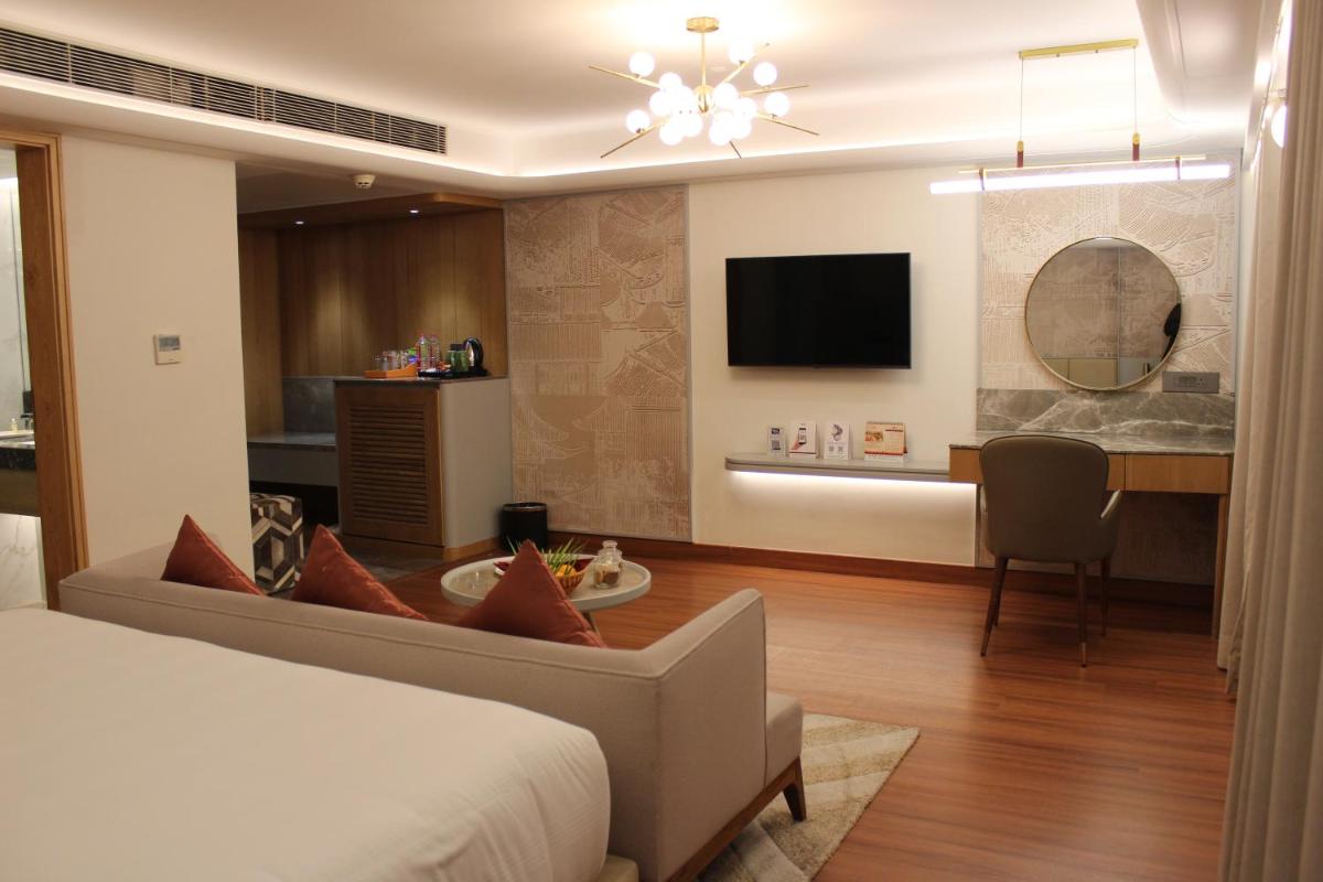a hotel room with a bed and a dining room at Pride Plaza Hotel, Ahmedabad in Ahmedabad