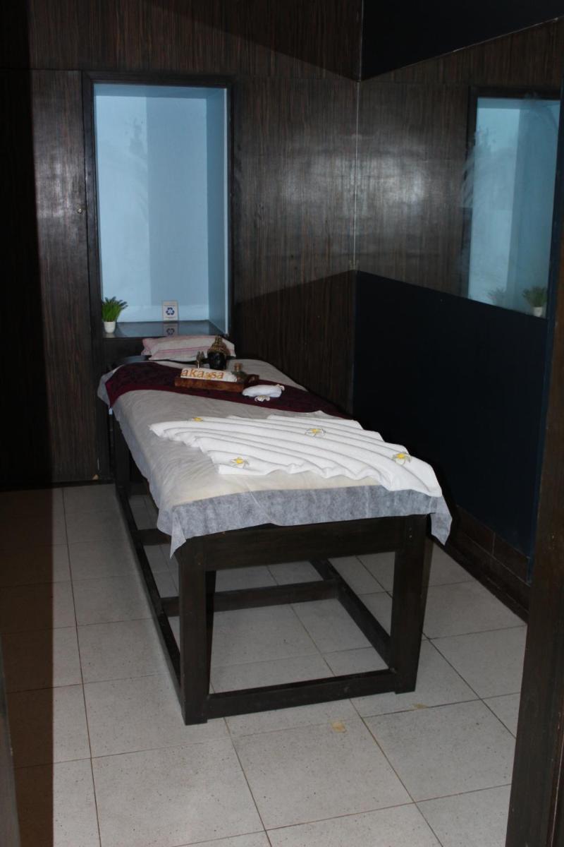 a bed in a room next to a window at Pride Plaza Hotel, Ahmedabad in Ahmedabad