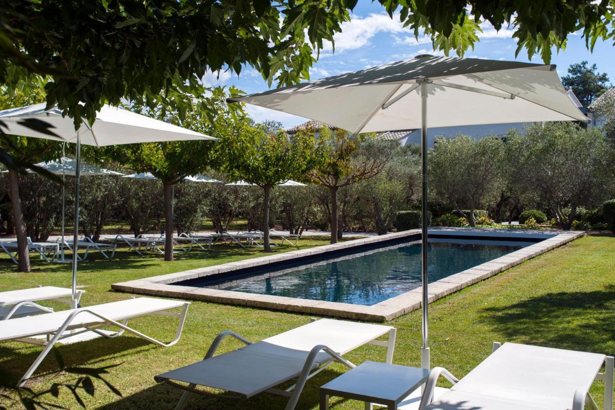 - une piscine avec 2 parasols et des chaises dans l'établissement Bdesign & Spa, à Paradou