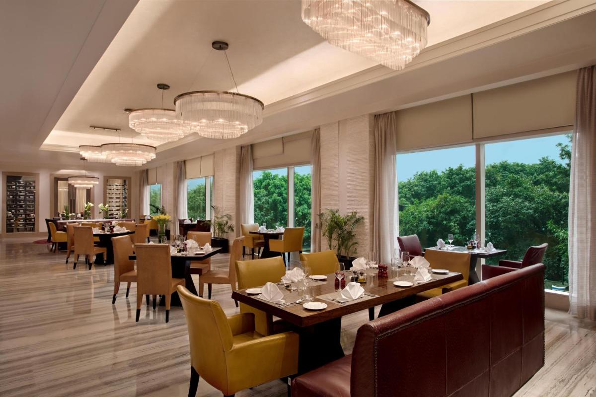 a dining room with tables and chairs and windows at Le Meridien Gurgaon, Delhi NCR in Gurgaon a dining room with tables and chairs and windows at Le Meridien Gurgaon, Delhi NCR in Gurgaon