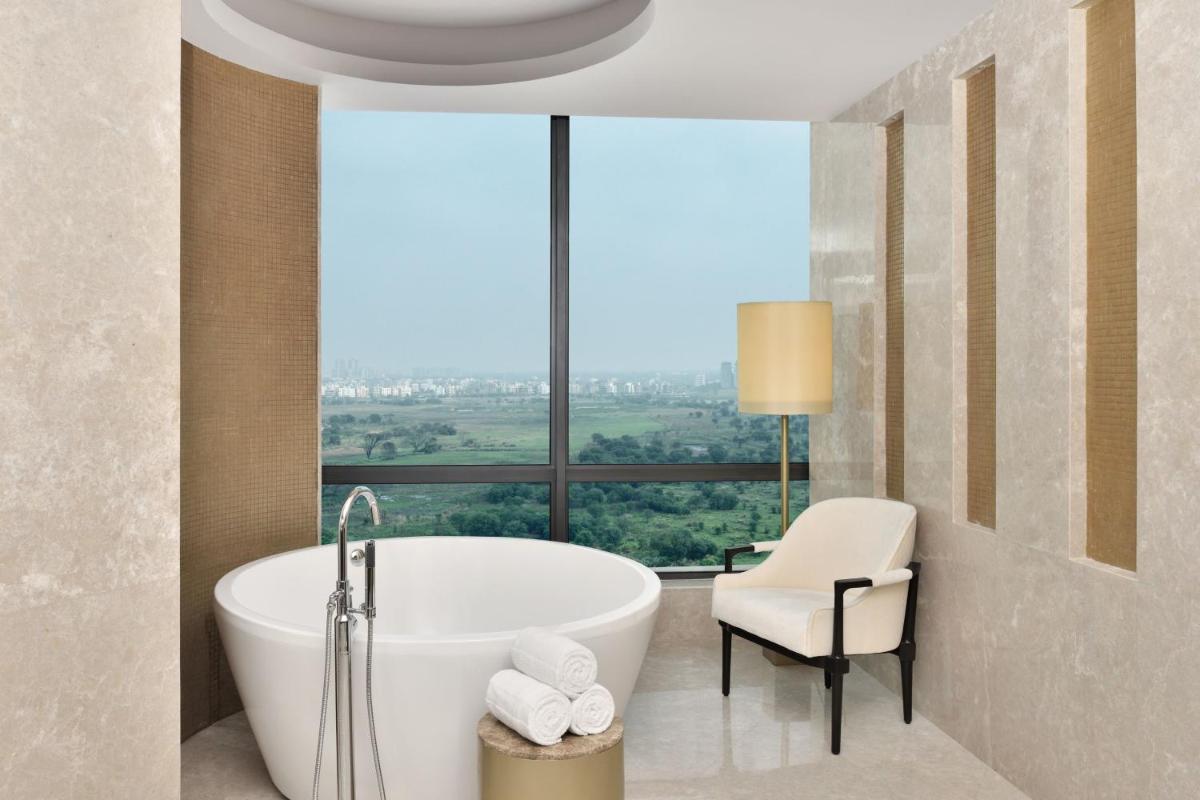 a bathroom with a tub and a chair and a window at The Westin Kolkata Rajarhat in Kolkata a bathroom with a tub and a chair and a window at The Westin Kolkata Rajarhat in Kolkata