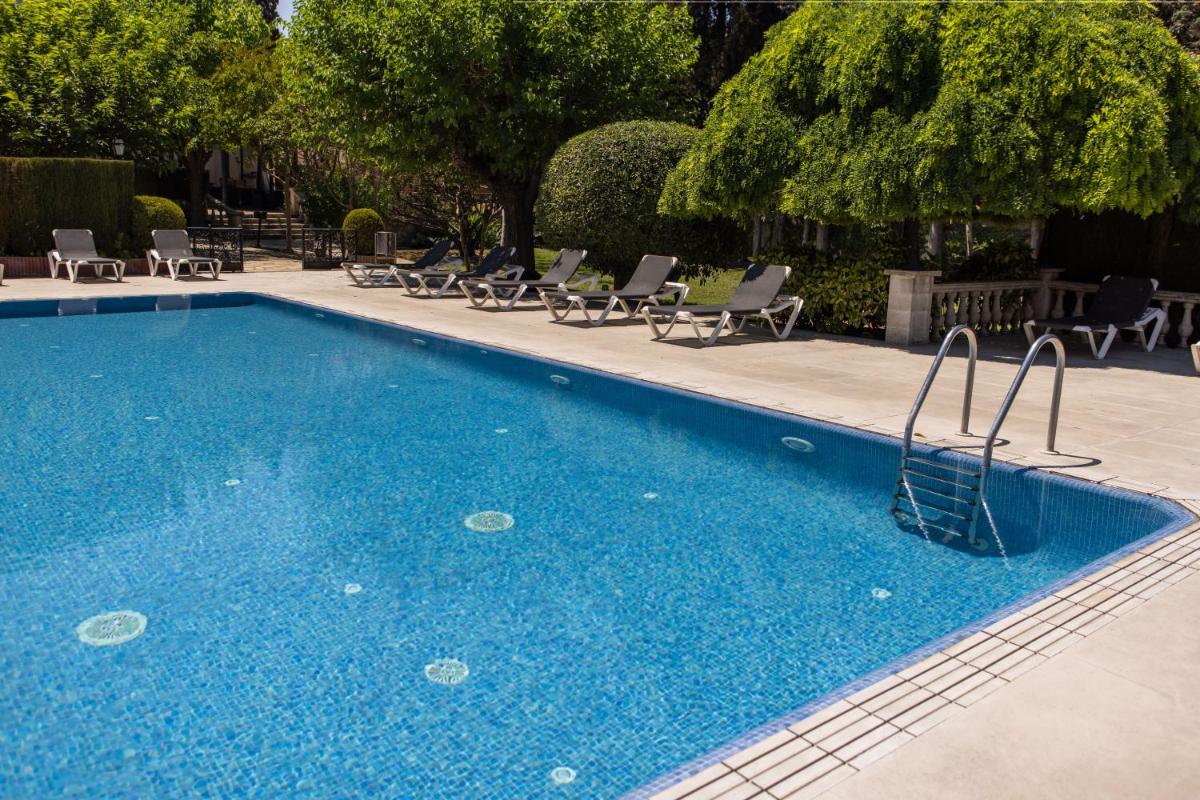 una gran piscina azul con tumbonas junto a ella en RVHotels Broquetas Spa Termal, en Caldes de Montbui