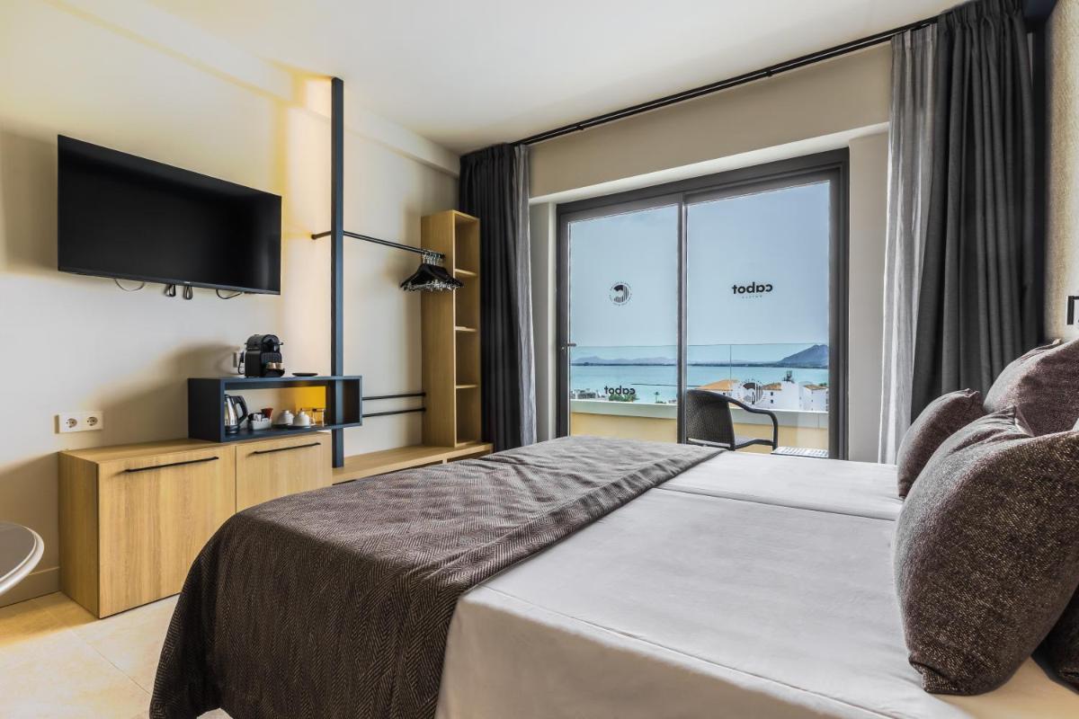 Una habitación de hotel con una cama grande y una ventana grande. en Cabot Pollensa Park Spa, en Puerto Pollensa