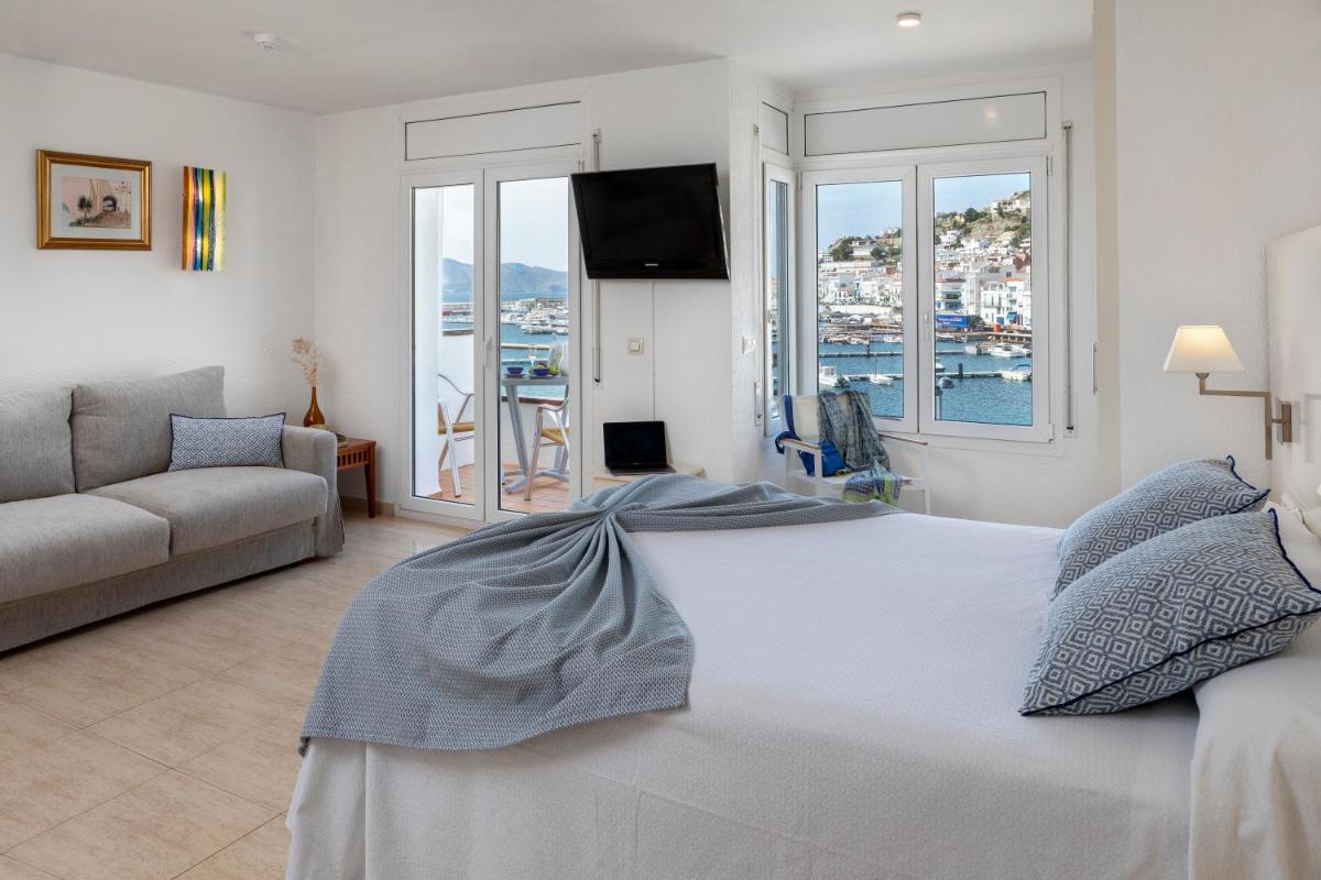 Un dormitorio con una gran cama blanca y un sofá. en Hotel Spa Cap de Creus, en Port de la Selva