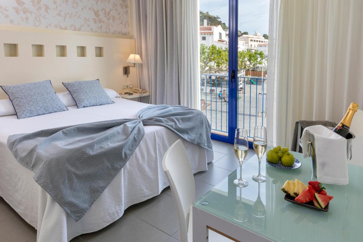 Una habitación de hotel con una cama y una mesa con copas de vino. en Hotel Spa Cap de Creus, en Port de la Selva