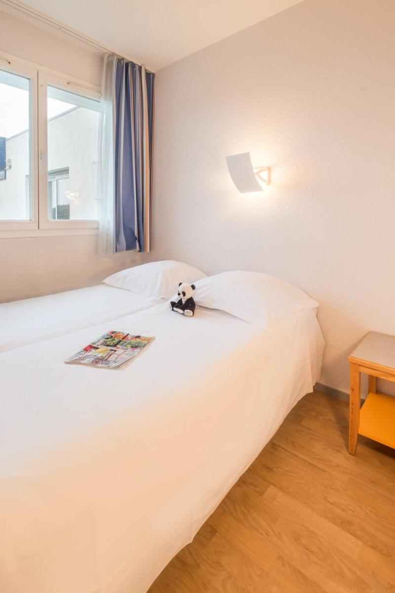 un lit avec un ours en peluche assis sur lui dans l'établissement Résidence Pierre & Vacances la Corniche de la Plage, à Bénodet