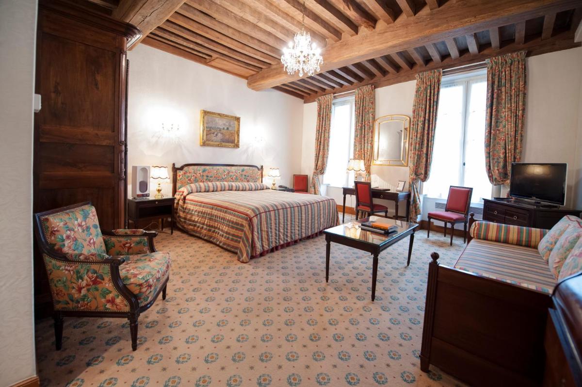 une chambre d'hôtel avec un lit et un canapé dans l'établissement Hôtel Le Cep & Spa, à Beaune