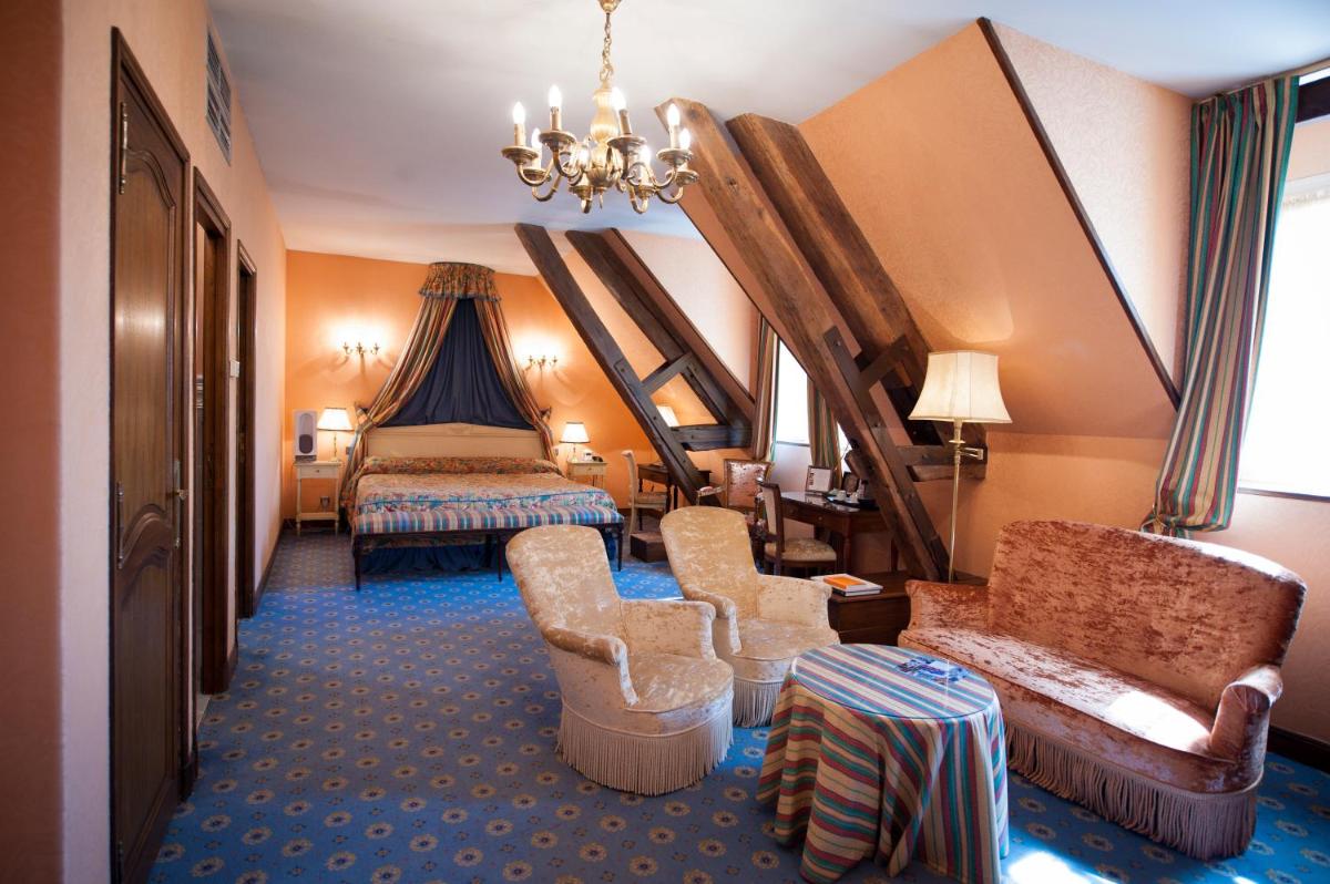 une chambre d'hôtel avec un lit, un canapé et des chaises dans l'établissement Hôtel Le Cep & Spa, à Beaune