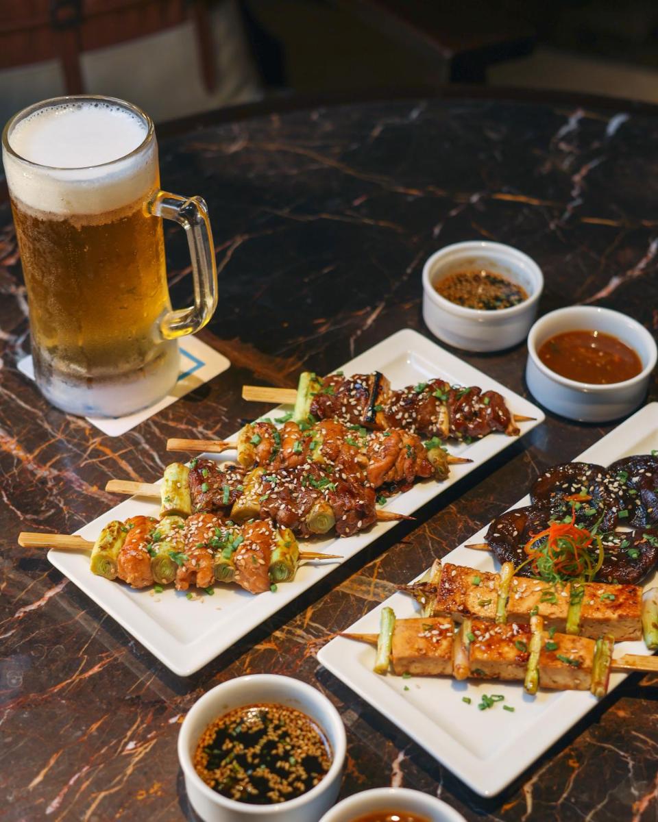 a table with plates of food and a glass of beer at Hilton Chennai in Chennai