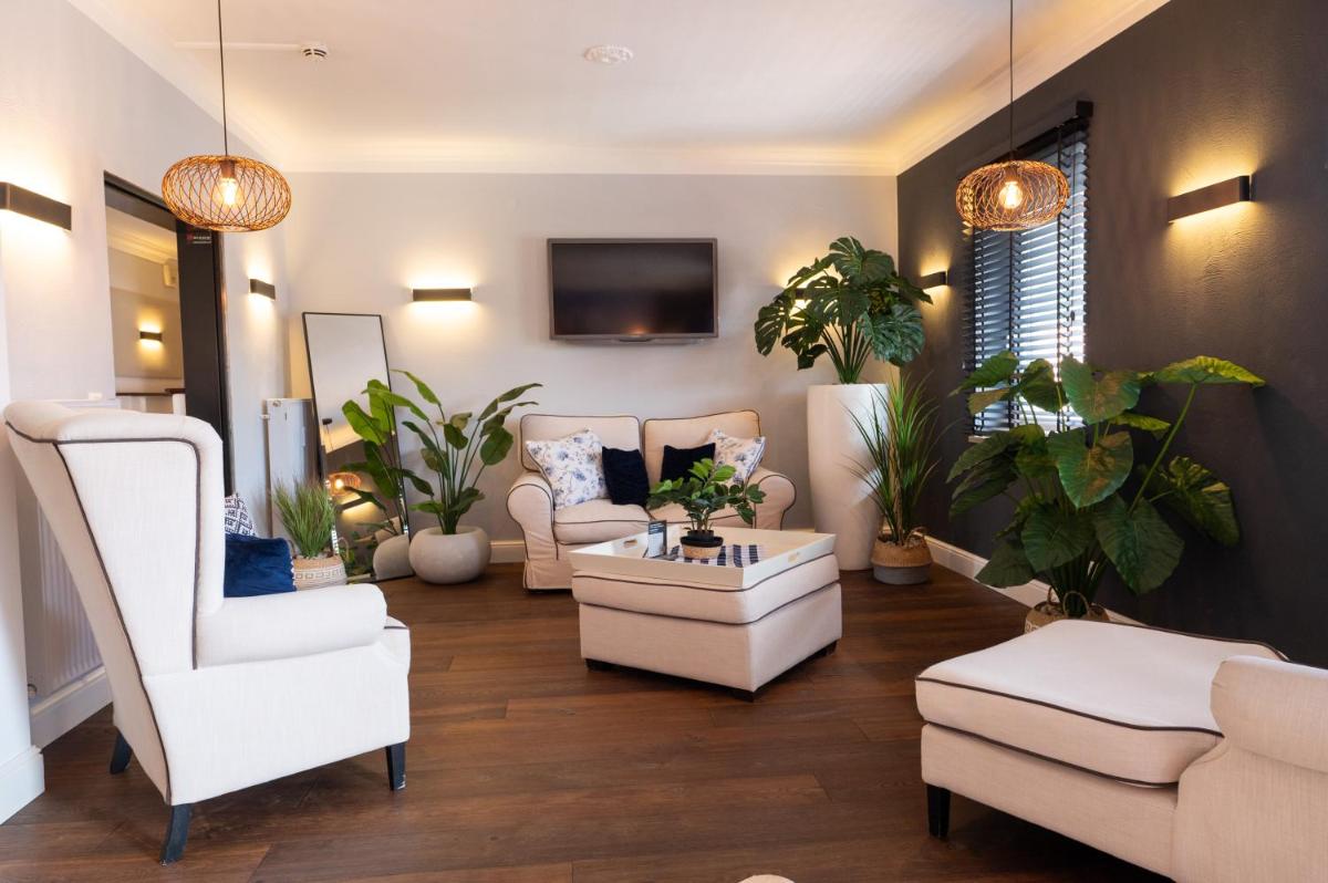 ein Wohnzimmer mit weißen Möbeln und Topfpflanzen in der Unterkunft ALPENLIEBE - Sauna & Whirlpool - APARTments in Inzell
