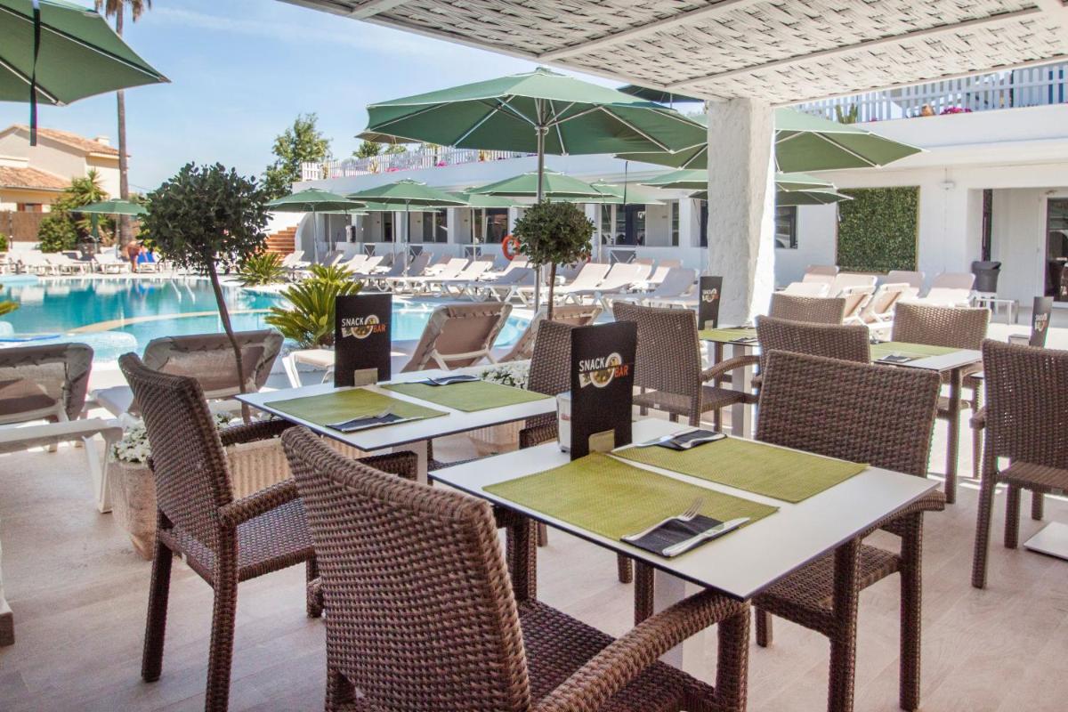 Un restaurante con mesas y sillas y una piscina. en Catalonia del Mar - Adults Only, en Cala Bona
