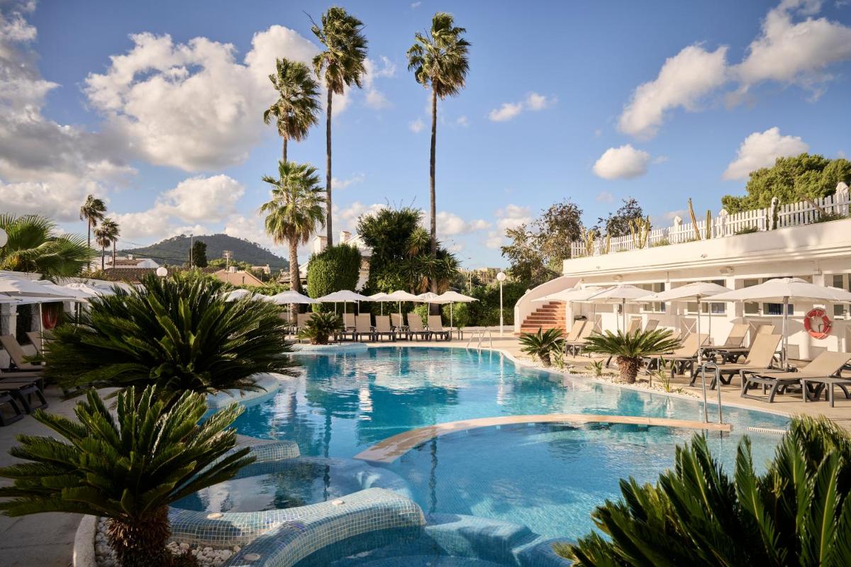 Una gran piscina con palmeras y un edificio. en Catalonia del Mar - Adults Only, en Cala Bona