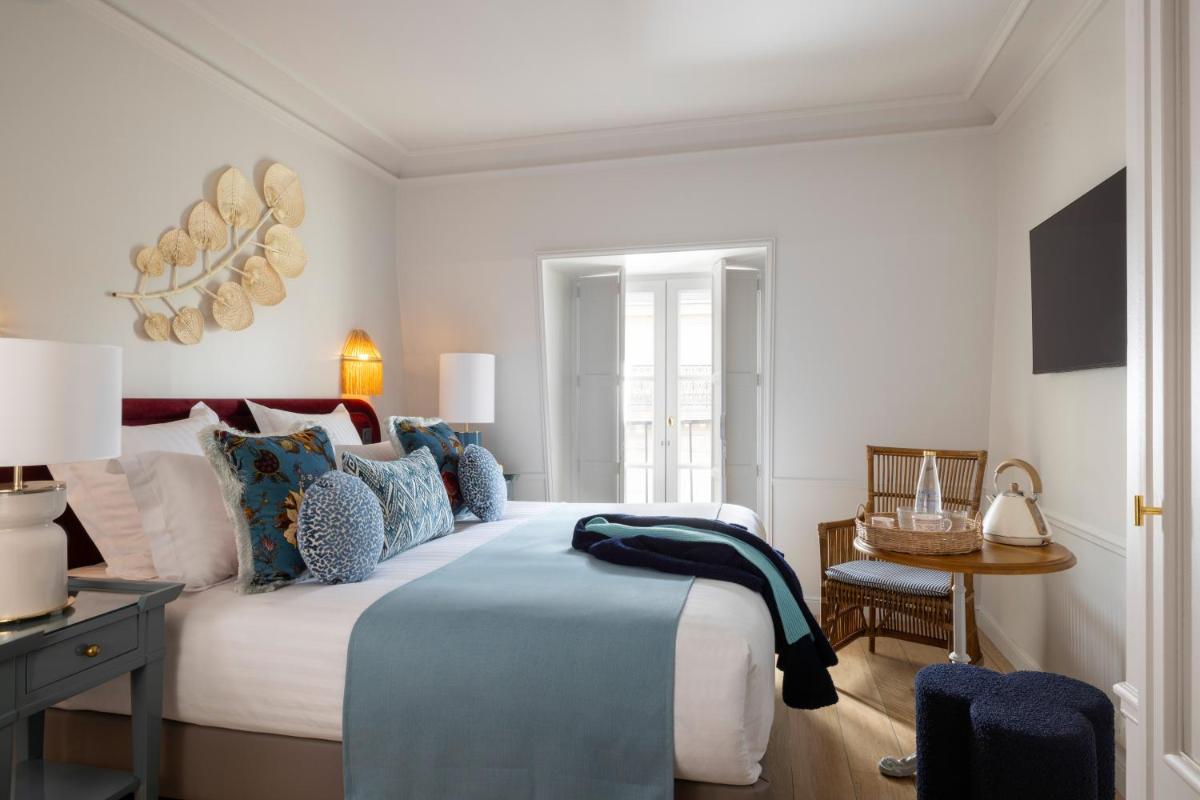 une chambre avec un grand lit aux oreillers bleus dans l'établissement Hôtel Le Lavoisier & Spa, à Paris