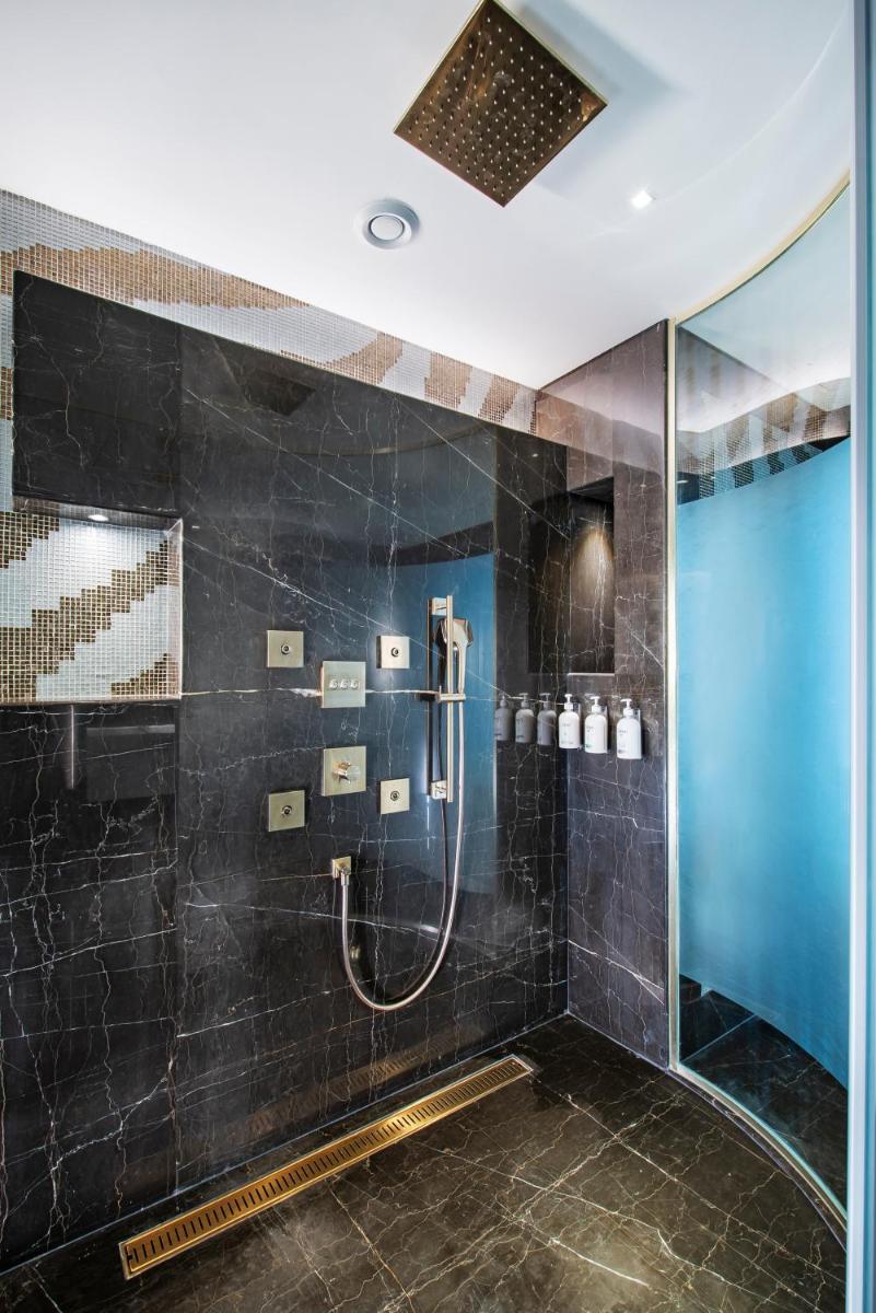 a bathroom with a shower with black tiles at Radisson Blu Hotel & Suites GRT Chennai in Chennai