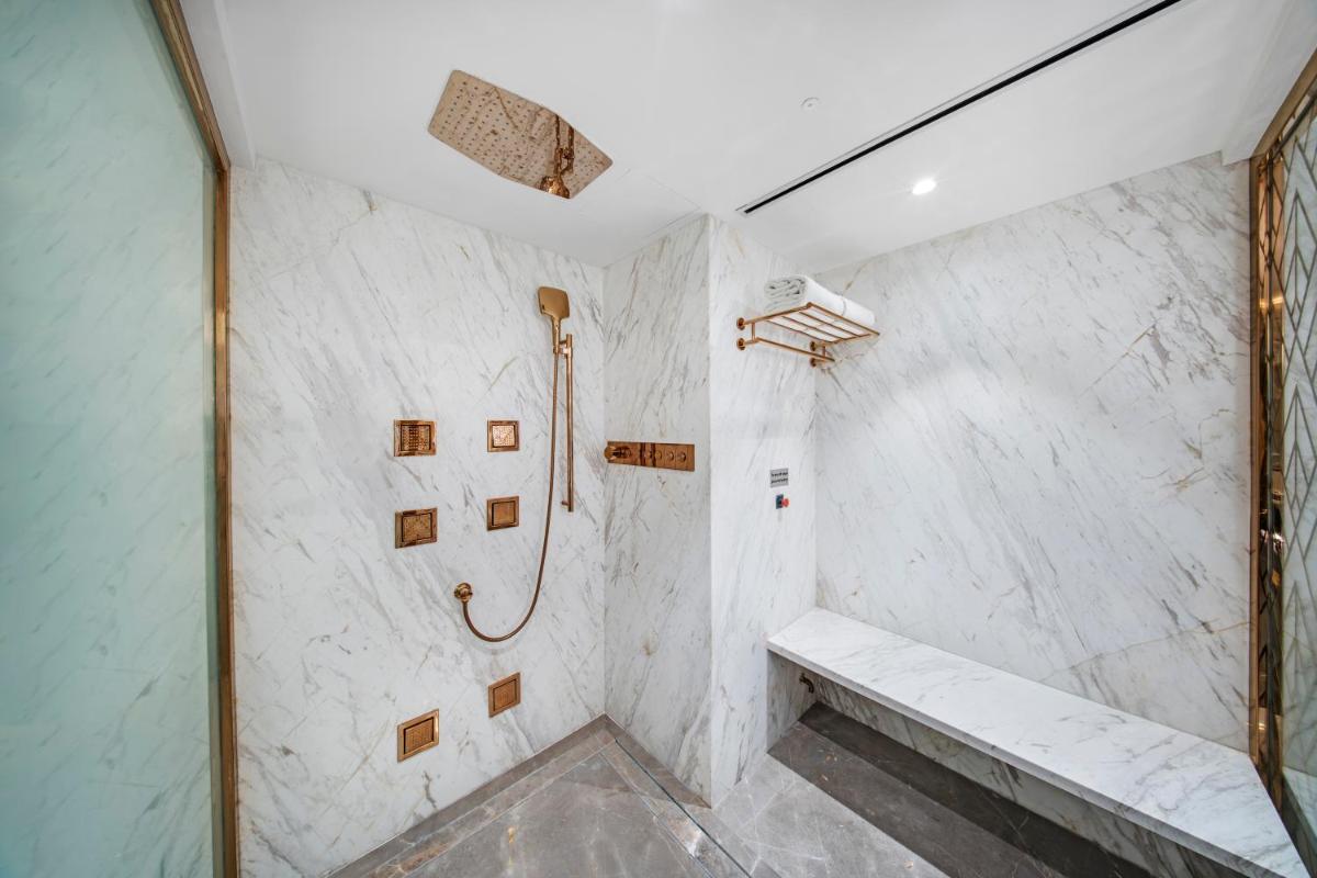 a bathroom with a shower with a bench at Radisson Blu Hotel & Suites GRT Chennai in Chennai