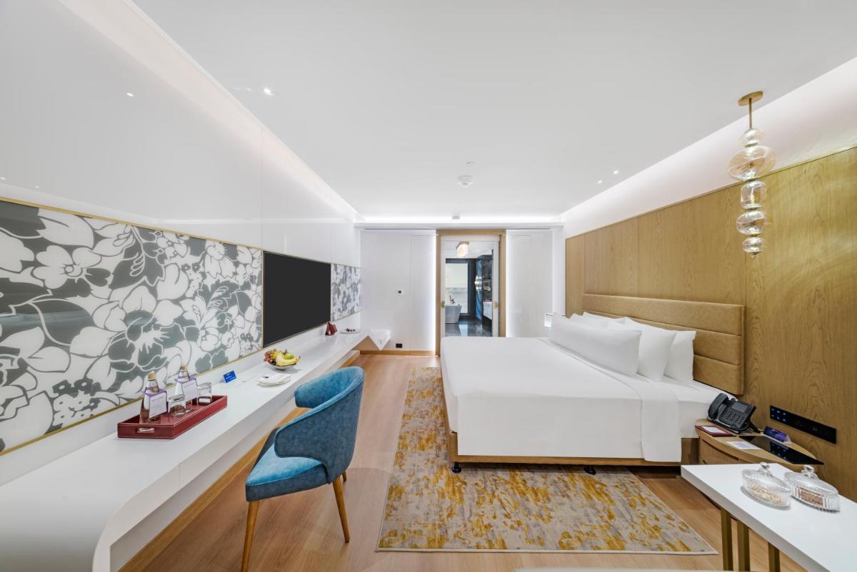 a hotel room with a white bed and a blue chair at Radisson Blu Hotel & Suites GRT Chennai in Chennai