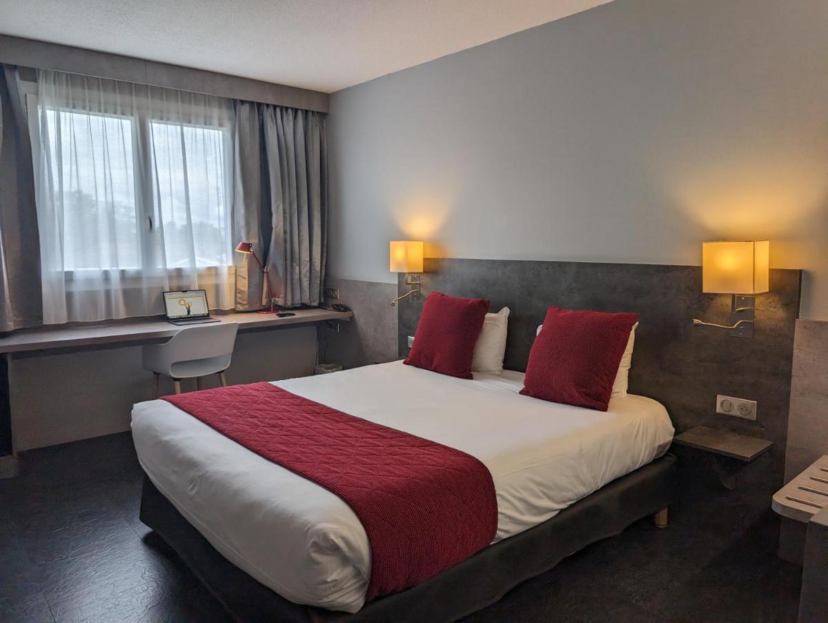 une chambre d'hôtel avec un grand lit avec des oreillers rouges dans l'établissement Hotel L'Hotan, à Portet-sur-Garonne 22 autres photos