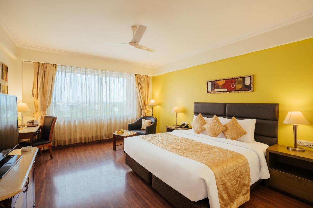 a hotel room with a large bed and a desk at The Piccadily in Lucknow