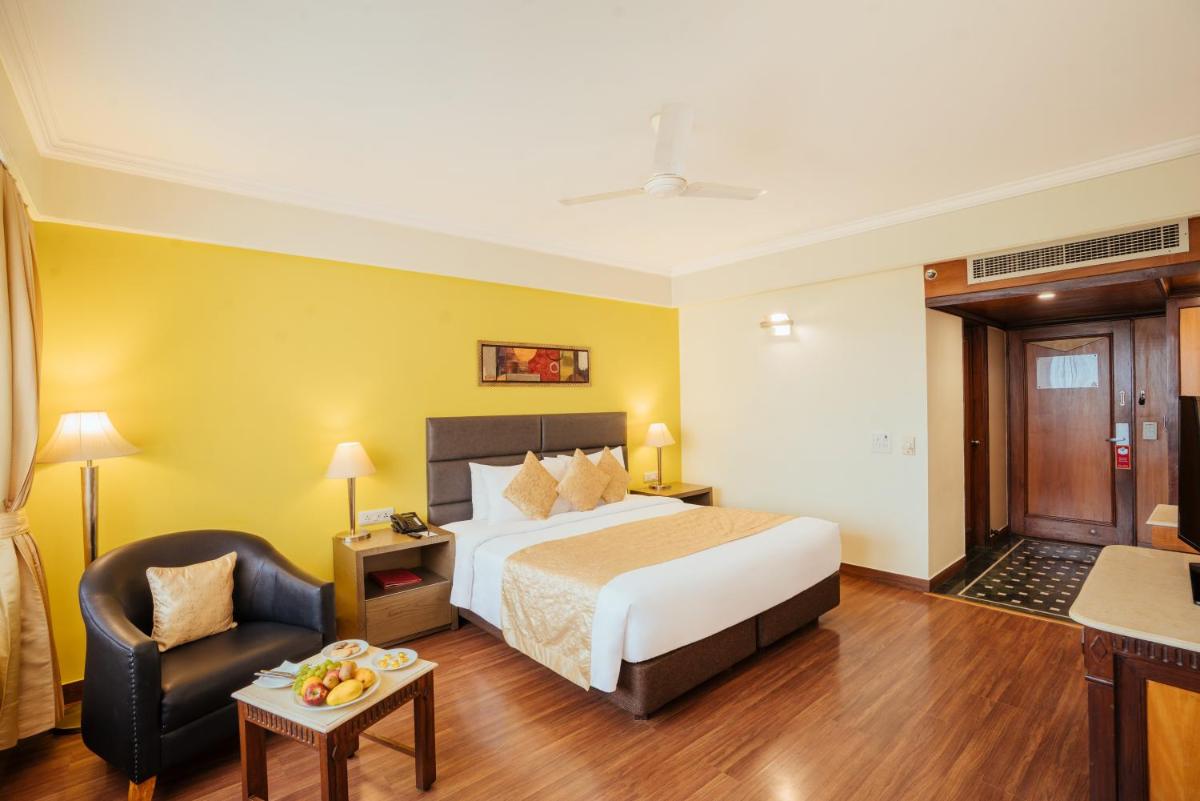 a hotel room with a bed and a chair at The Piccadily in Lucknow