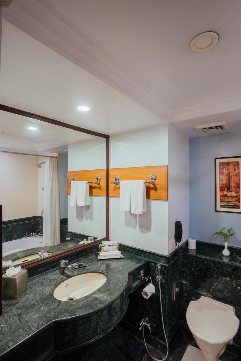 a bathroom with a sink and a large mirror at The Piccadily in Lucknow