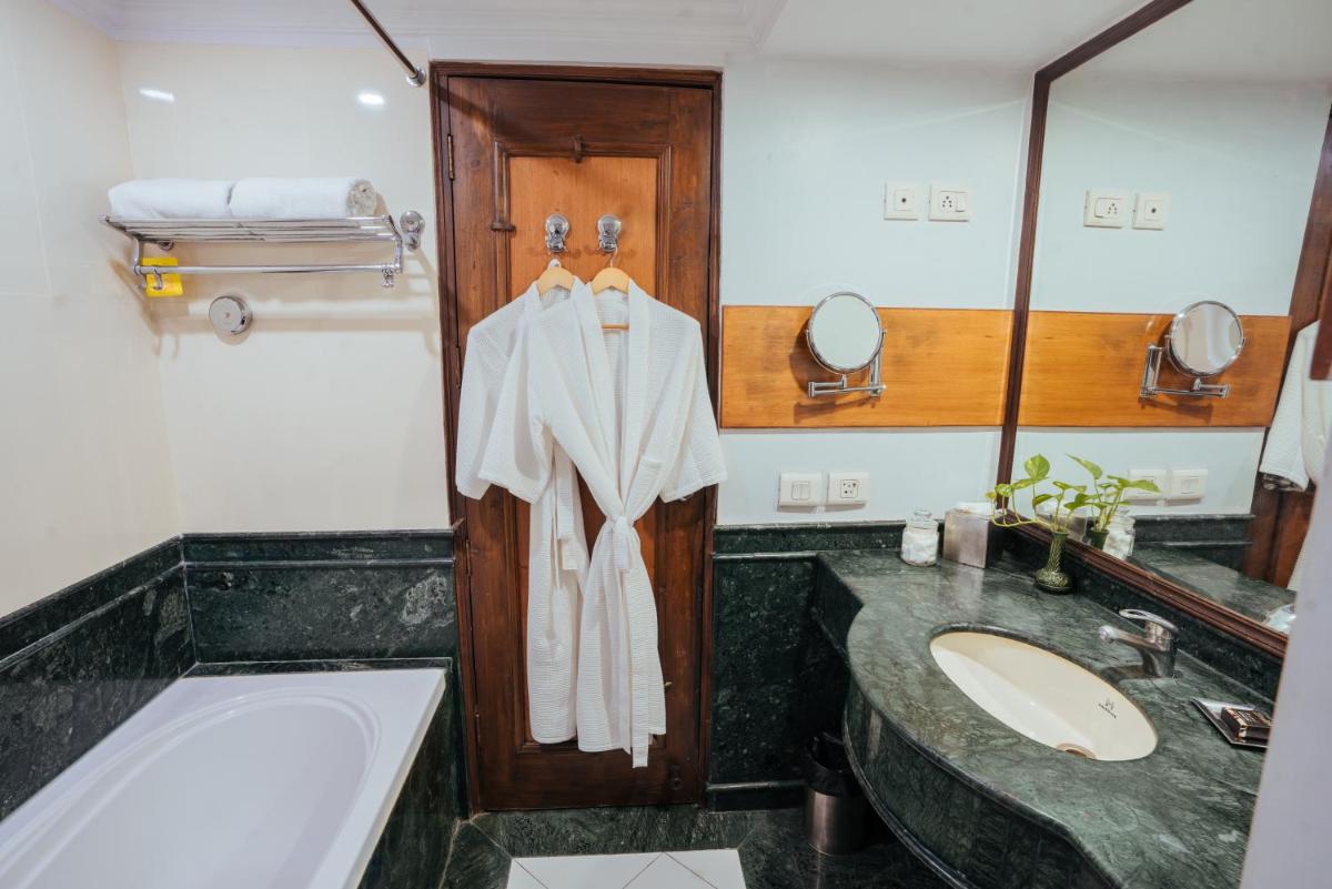 a bathroom with a sink and a robe hanging on a door at The Piccadily in Lucknow