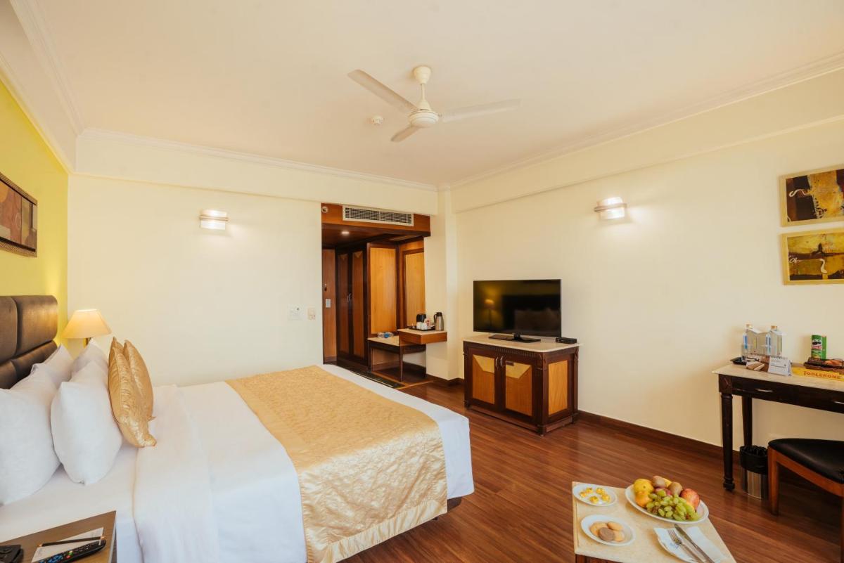 a hotel room with a bed and a television at The Piccadily in Lucknow
