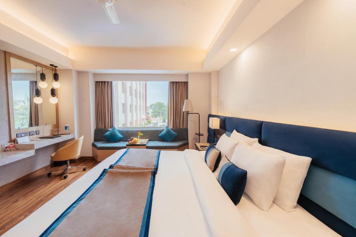 a hotel room with a large bed and a couch at The Piccadily in Lucknow