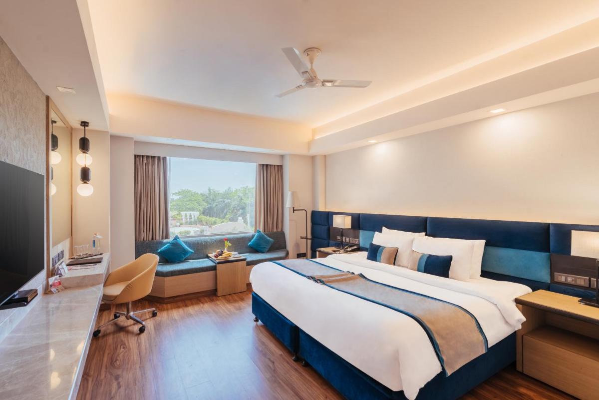 a hotel room with a large bed and a desk at The Piccadily in Lucknow