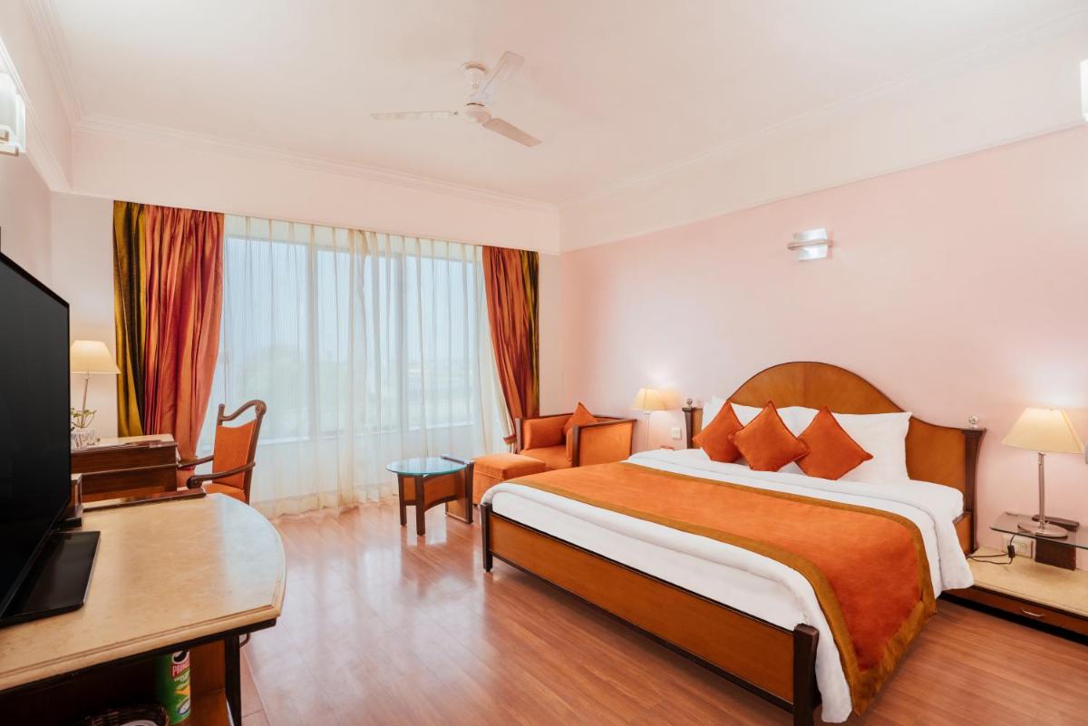 a hotel room with a bed and a television at The Piccadily in Lucknow