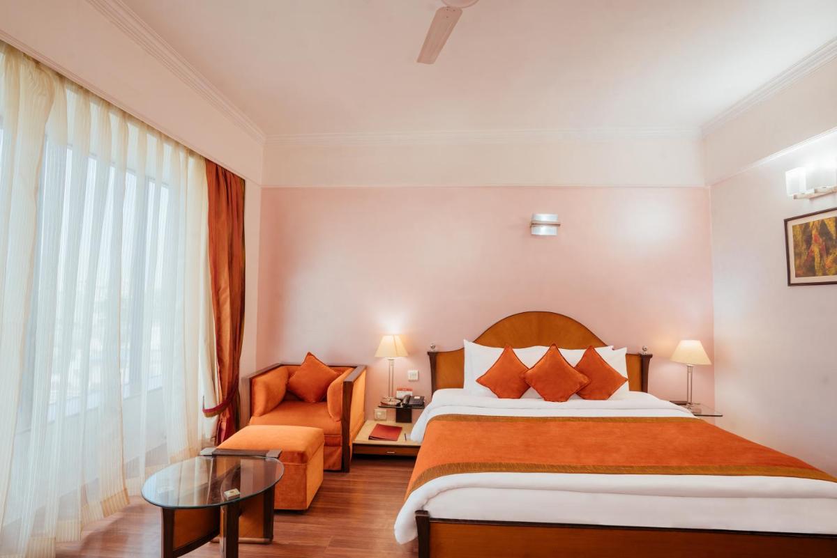 a hotel room with a bed and a chair at The Piccadily in Lucknow