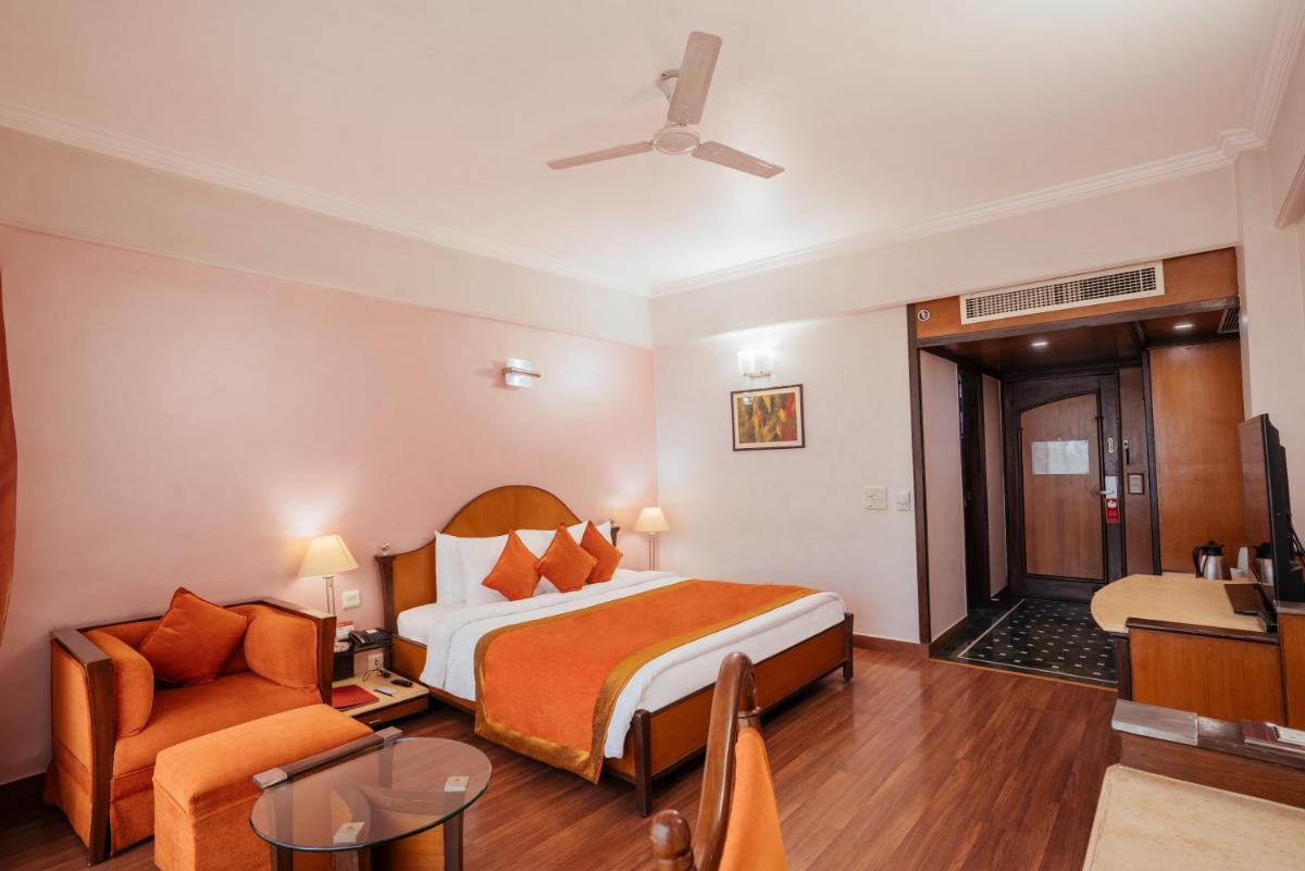 a hotel room with a bed and a chair at The Piccadily in Lucknow