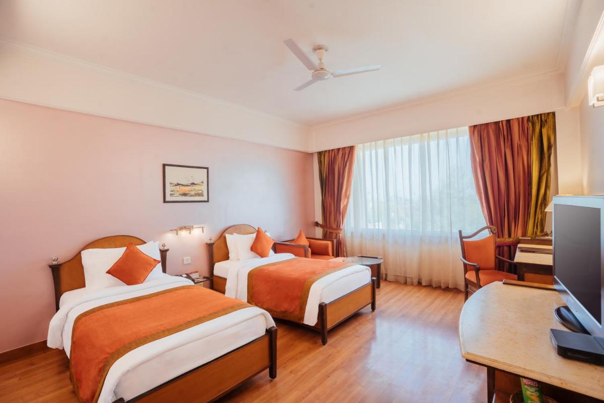 a hotel room with two beds and a television at The Piccadily in Lucknow