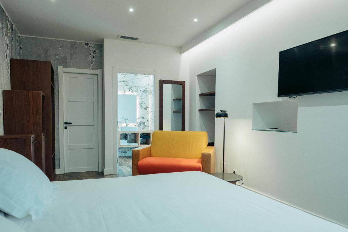 - une chambre avec un lit et une chaise jaune dans l'établissement Hôtel Casale Olmia, à Moncale