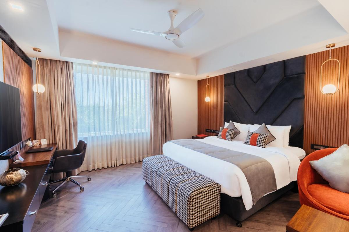 a hotel room with a large bed and a desk at The Piccadily in Lucknow