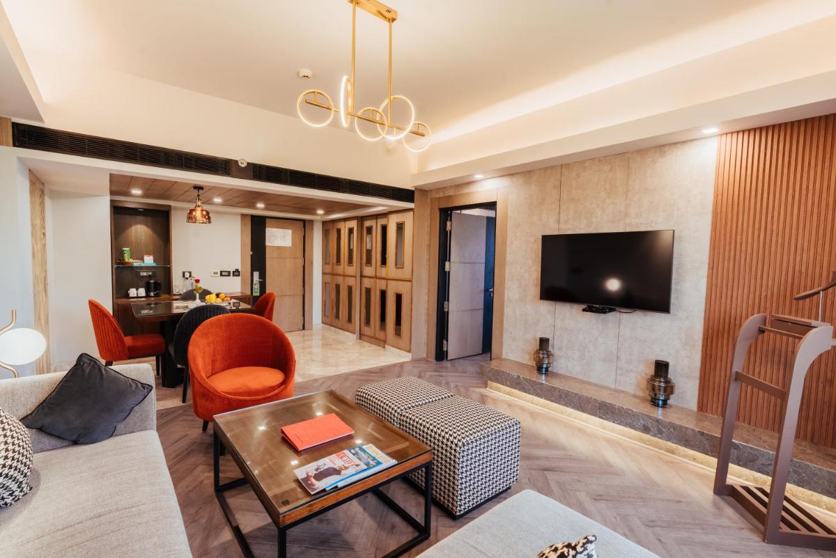 a living room with a couch and a tv on a wall at The Piccadily in Lucknow